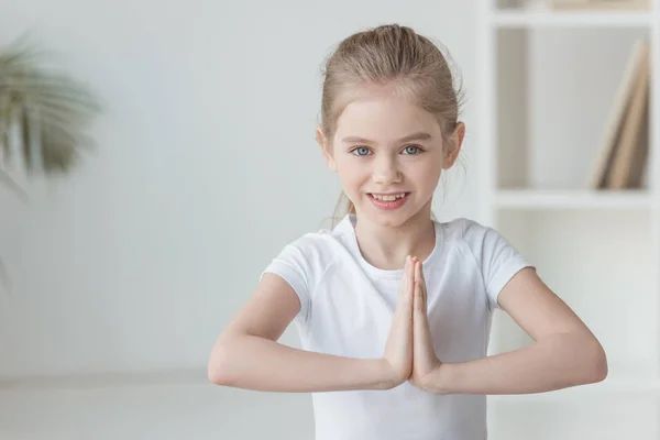 Bambino sorridente che pratica yoga e fa gesto namaste — Foto stock