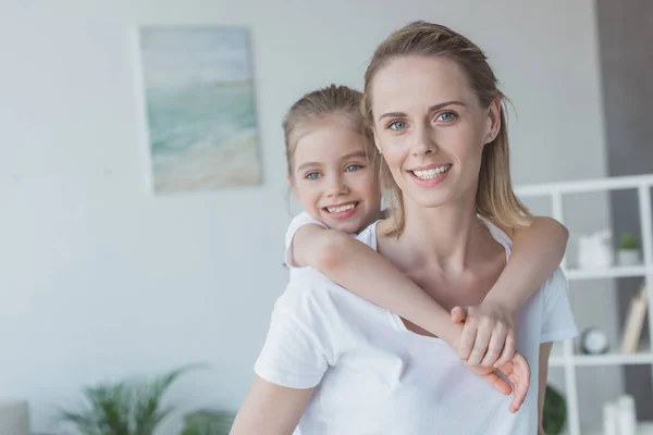 Beautiful little daughter piggybacking on her happy mother — Stock Photo