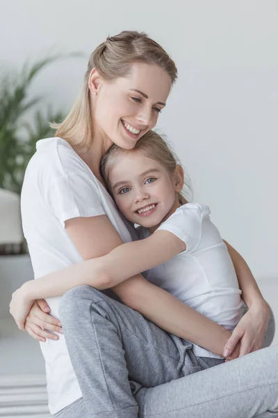 Glücklich schöne Mutter und Tochter umarmen und in die Kamera schauen — Stockfoto