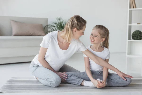 Mutter lehrt Tochter, wie man in Yoga-Schmetterling-Pose sitzt — Stockfoto