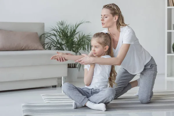 Madre enseñando a su hija a calentar los hombros antes de los ejercicios - foto de stock