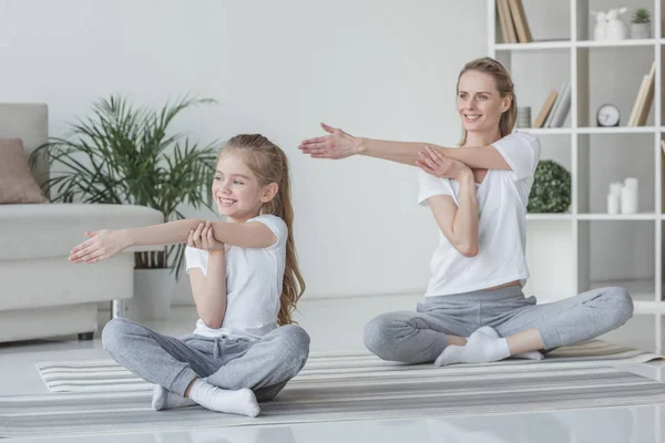 Mãe e filha aquecendo os ombros antes do treinamento — Fotografia de Stock