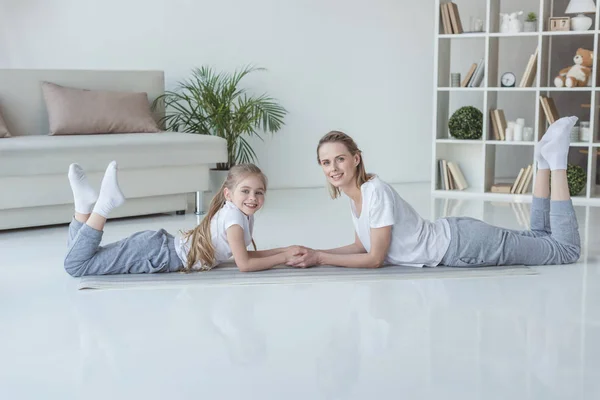 Relaxed mother and daughter lying on floor together and looking at camera — Stock Photo