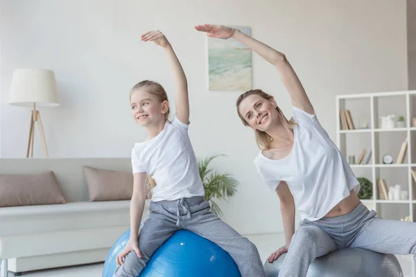 Madre e figlia facendo curve laterali su palle in forma — Foto stock