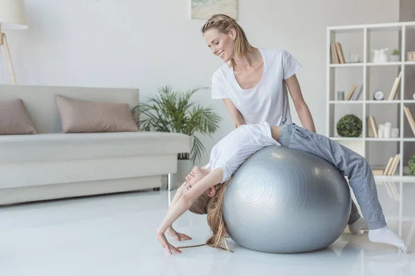 Mãe ensinando sua filha a ficar na roda de ioga posar com bola em forma — Fotografia de Stock