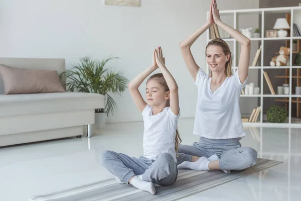 Mãe e filha praticando ioga em lótus posar em casa — Fotografia de Stock