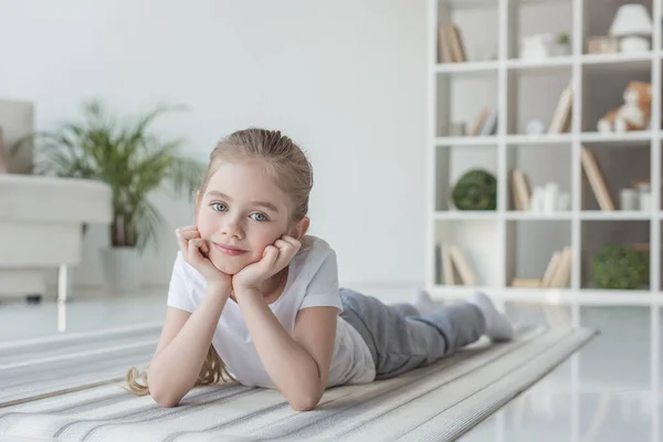 Lächelndes kleines Kind auf Yogamatte liegend und in die Kamera blickend — Stockfoto