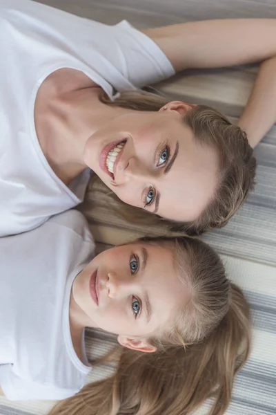 Vue de dessus de la mère et de la fille regardant la caméra tout en se relaxant — Photo de stock