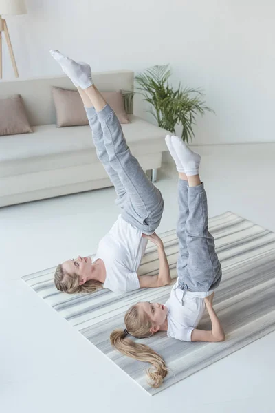 Mother and daughter practicing yoga in Supported Shoulder Stand pose at home — Stock Photo