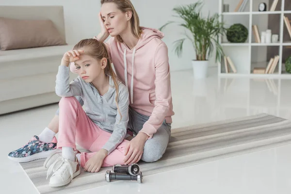 Exhausted mother and daughter relaxing on yoga mat after training — Stock Photo