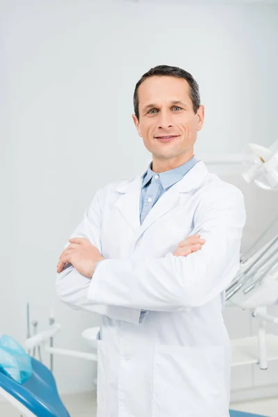 Selbstbewusster Arzt mit verschränkten Armen in moderner Zahnklinik — Stockfoto