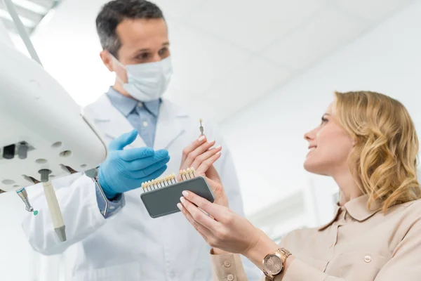 Doctor showing tooth implants to female patient in modern dental clinic — Stock Photo