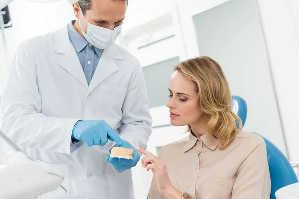 Médecin et patient regardant le modèle de mâchoires dans la clinique dentaire moderne — Photo de stock