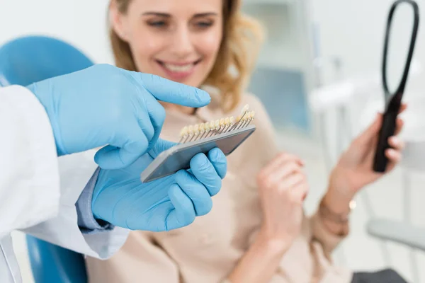 Médico escolhendo implantes dentários com paciente feminino na clínica odontológica moderna — Fotografia de Stock