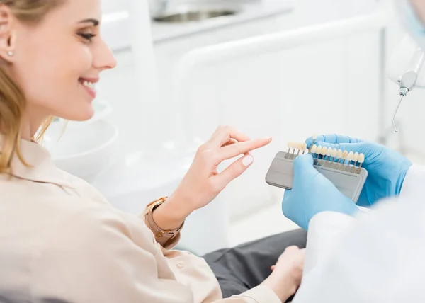 Doctor showing tooth implants to female patient in modern dental clinic — Stock Photo