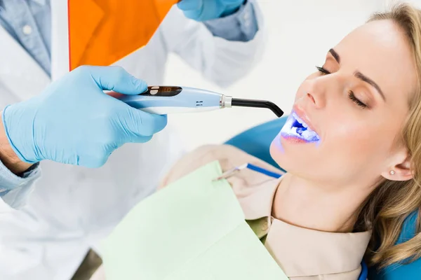 Dentist using uv lamp to treat patient teeth in modern dental clinic — Stock Photo