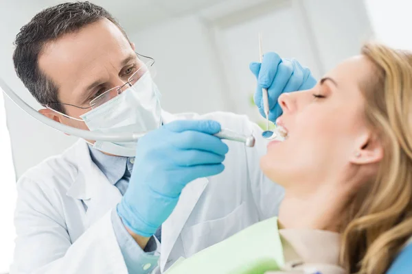 Médecin traite les dents des patients dans la clinique dentaire moderne — Photo de stock