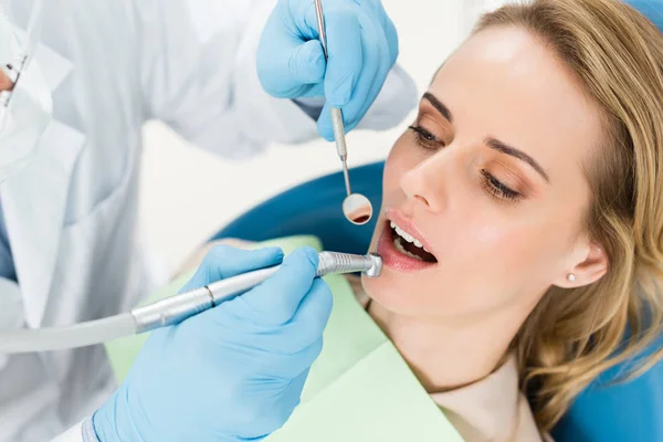Doctor using dental drill during procedure in modern dental clinic — Stock Photo