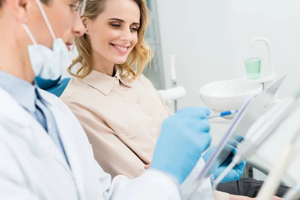 Arzt, der die Diagnose während der Konsultation mit dem Patienten in einer modernen Zahnklinik aufzeichnet — Stockfoto