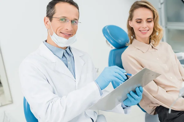 Diagnostic d'enregistrement de médecin tout en consultant le patient dans la clinique dentaire moderne — Photo de stock