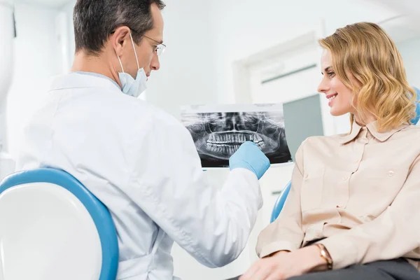 Mujer consultando con dentista mirando rayos X en clínica moderna - foto de stock