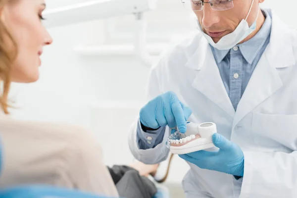 Doctor showing jaws model to female patient in modern dental clinic — Stock Photo