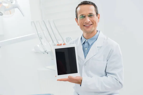 Dentista che mostra schermo tablet vuoto moderna clinica dentale — Foto stock