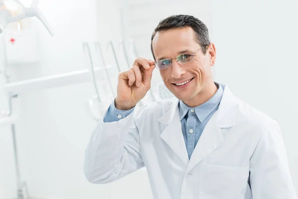Médico sonriente en gafas en clínica dental moderna - foto de stock
