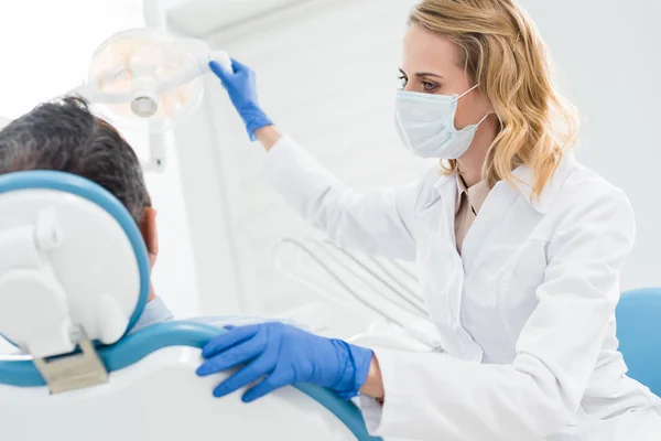 Doctor adjusting lamp in modern dental clinic — Stock Photo