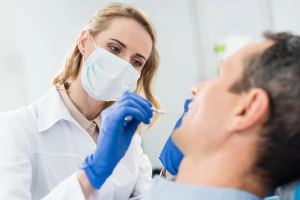 Arzt überprüft Patientenzähne mit Spiegel in moderner Zahnklinik — Stockfoto