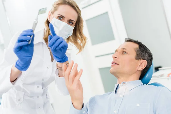 Une dentiste montre une radiographie masculine dans une clinique dentaire moderne — Photo de stock