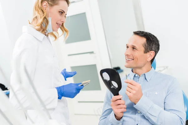 Paciente masculino escolhendo implante dentário na clínica odontológica moderna — Fotografia de Stock