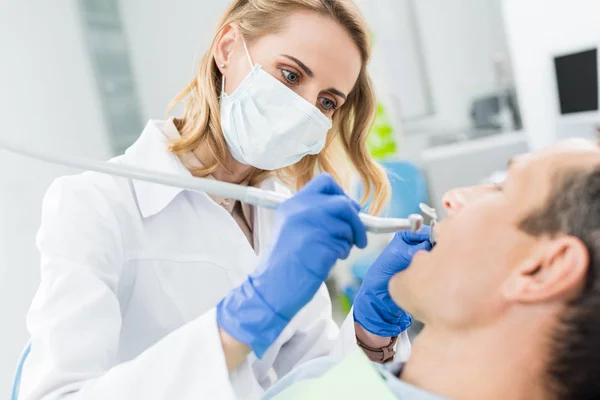 Médico usando broca dentária durante o procedimento na clínica odontológica moderna — Fotografia de Stock