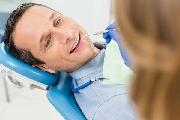 Dentista revisando dientes de paciente en clínica moderna - foto de stock