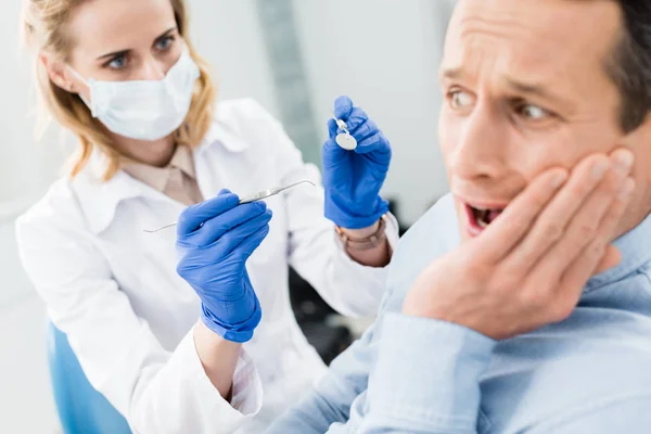 Paciente masculino tem medo de dentista na clínica odontológica moderna — Fotografia de Stock