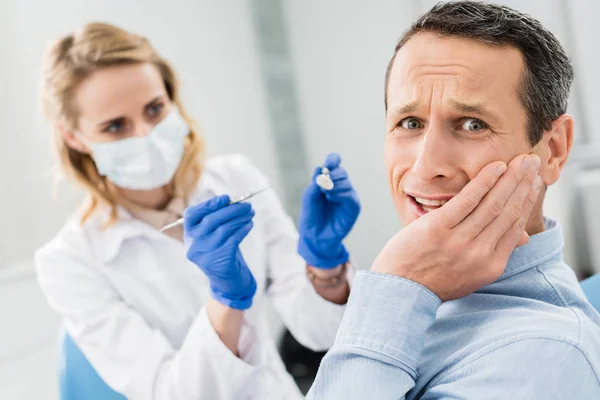 Dentista feminina verificando os dentes do paciente com espelho na clínica odontológica moderna — Fotografia de Stock