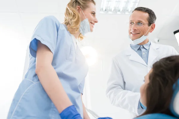 Médicos sonrientes y pacientes en clínica dental moderna - foto de stock