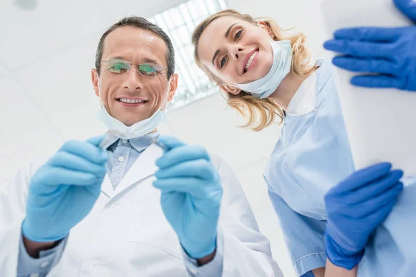 Dentistas revisando dientes de pacientes en clínica moderna - foto de stock