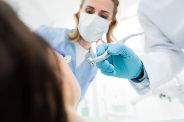 Médicos usando broca dentária durante o procedimento na clínica odontológica moderna — Fotografia de Stock