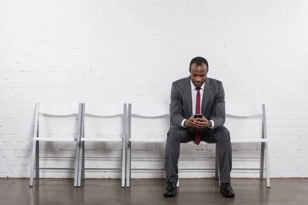 African american businessman with smartphone waiting for job interview — Stock Photo