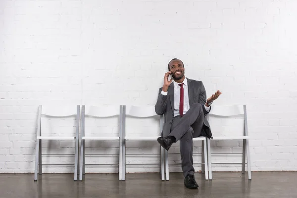 Afrikanischer amerikanischer Geschäftsmann telefoniert auf Smartphone, während er auf ein Vorstellungsgespräch wartet — Stockfoto