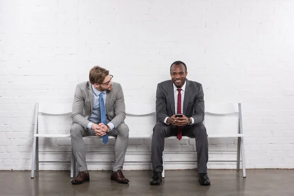 Empresários multiétnicos em ternos à espera de entrevista de emprego — Fotografia de Stock
