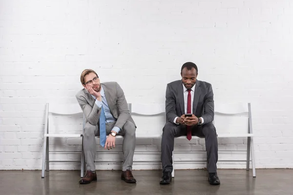 Hombres de negocios multiétnicos en trajes esperando entrevista de trabajo - foto de stock