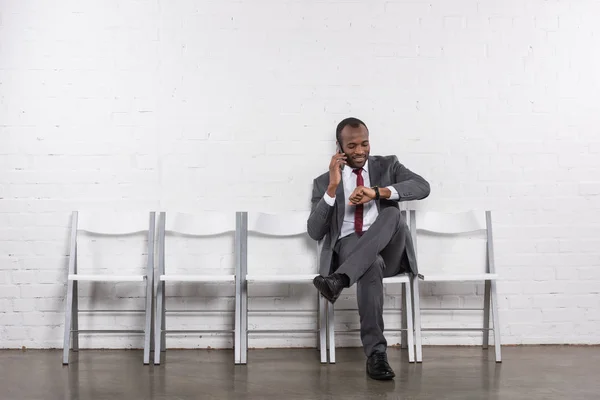 Afrikanischer amerikanischer Geschäftsmann telefoniert auf Smartphone, während er auf ein Vorstellungsgespräch wartet — Stockfoto