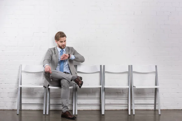 Caucásico empresario comprobar tiempo mientras espera a entrevista de trabajo - foto de stock