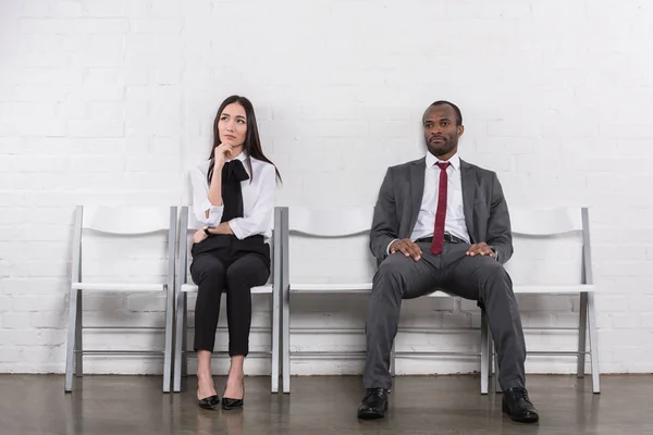 Asiático mujer de negocios y africano americano hombre de negocios a la espera de trabajo entrevista - foto de stock