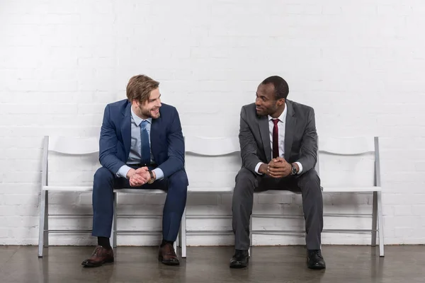 Uomini d'affari multiculturali sorridenti che si guardano in attesa di un colloquio di lavoro — Foto stock