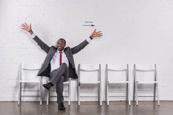 Sorridente empresário afro-americano com braços estendidos à espera de entrevista de emprego — Fotografia de Stock