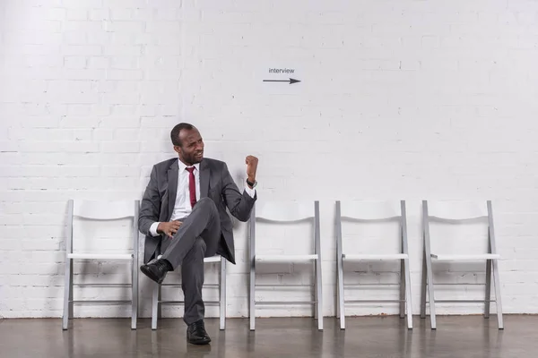 Homme d'affaires afro-américain montrant poing à quelqu'un en attendant un entretien d'embauche — Photo de stock