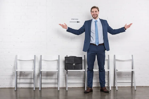 Happy caucasian businessman standing near empty chairs while waiting for job interview — Stock Photo